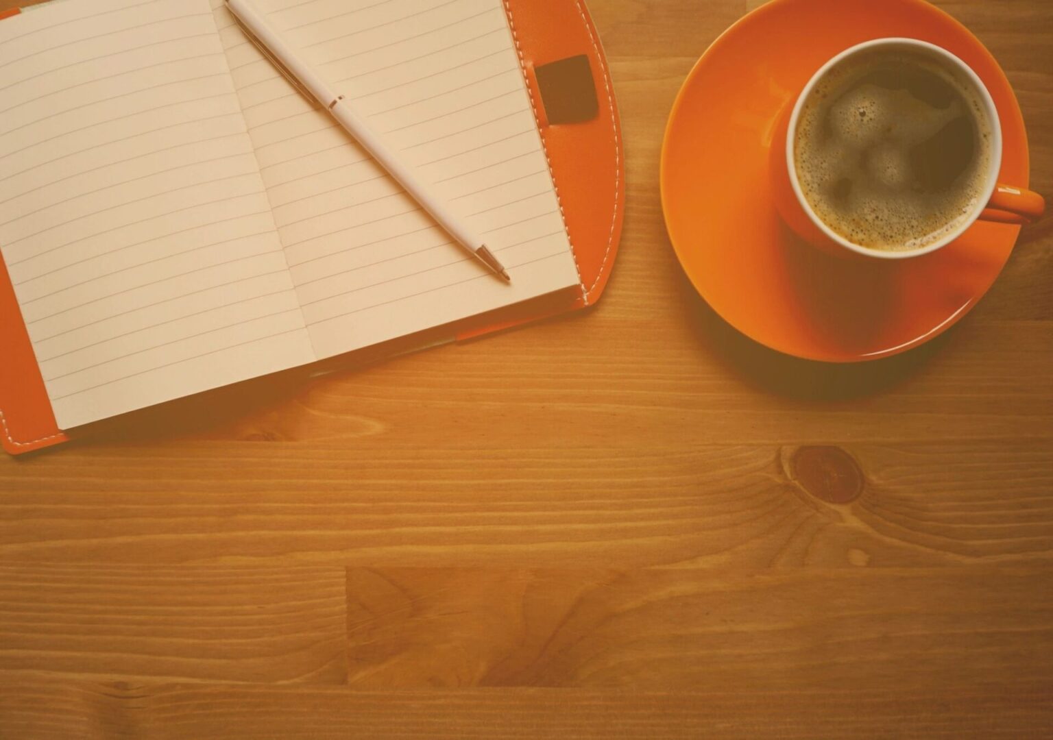 A cup of coffee and an open notebook on the table.